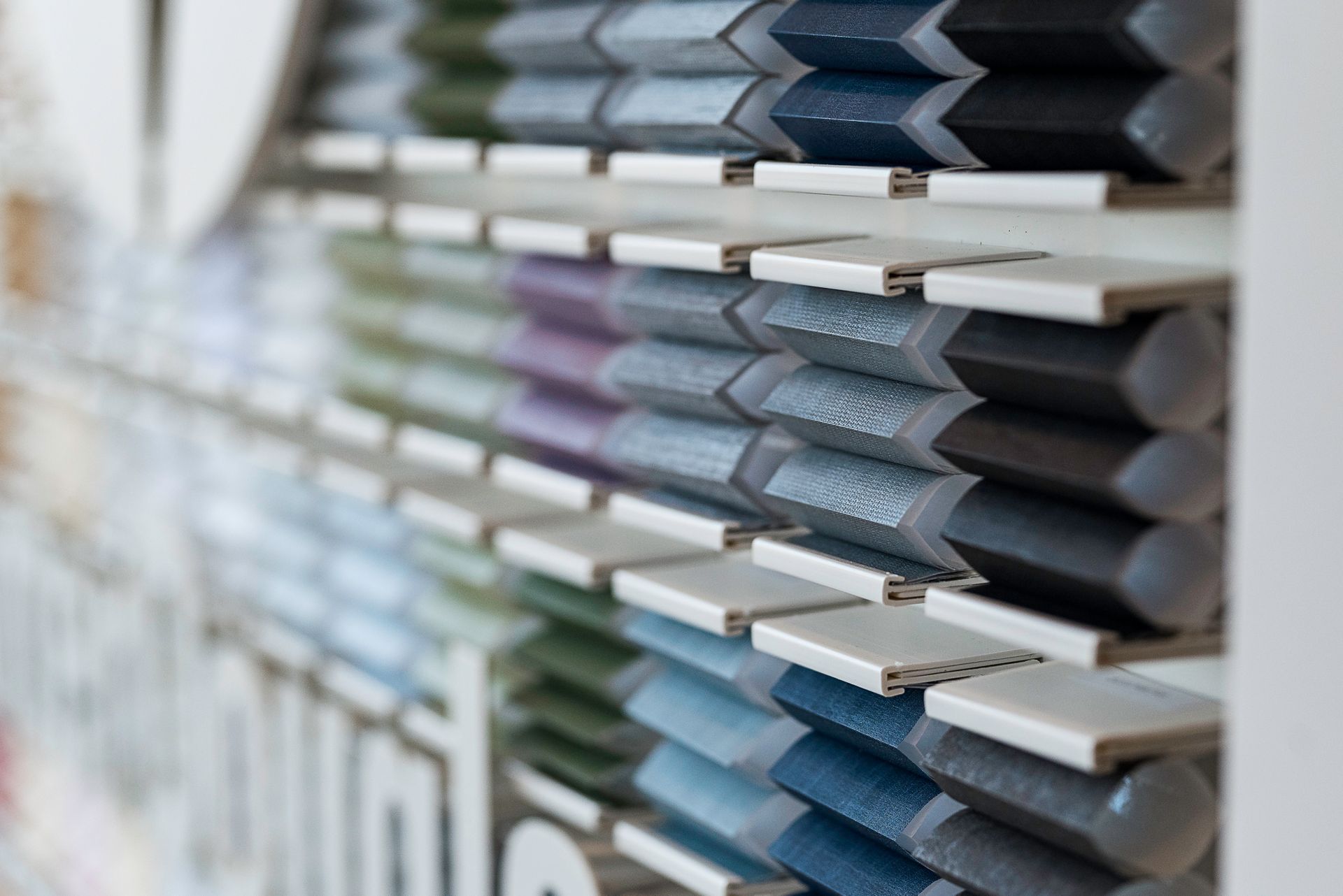Stacks of blue and gray sample materials on white shelves in a showroom