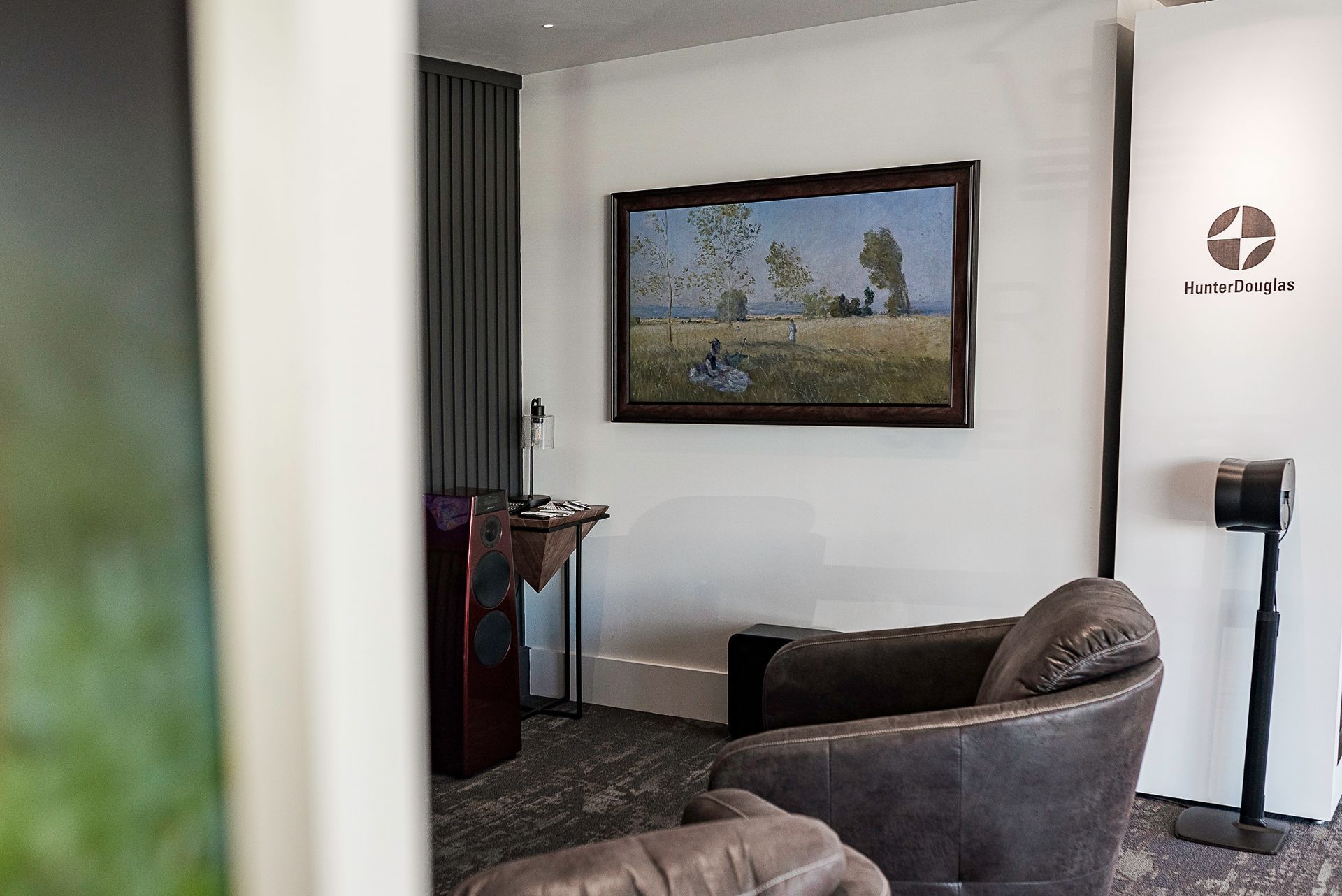 Small lounge with brown chairs, framed landscape art, patterned carpet, and wall-mounted TV