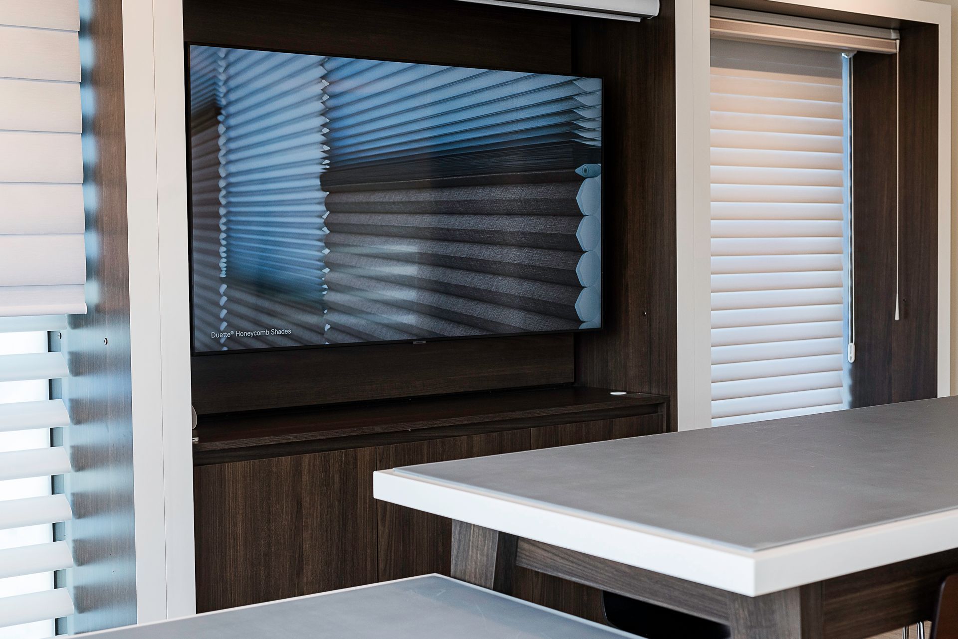 Modern outdoor kitchen with built-in grill, wood cabinetry, and a white countertop under a covered patio