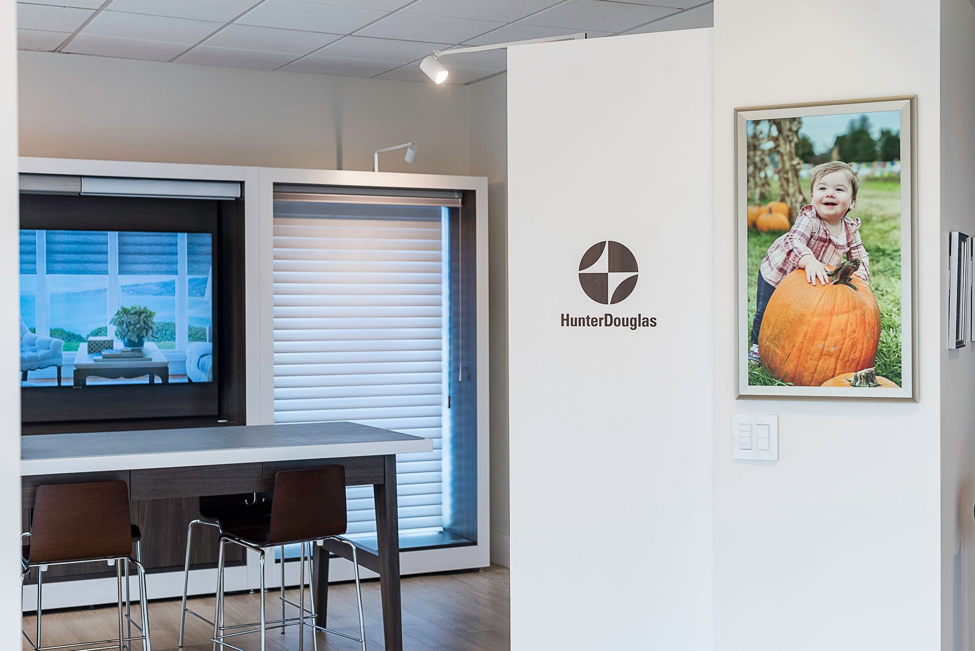 Office waiting area with table, chairs, windows, logo, and a framed photo on the wall