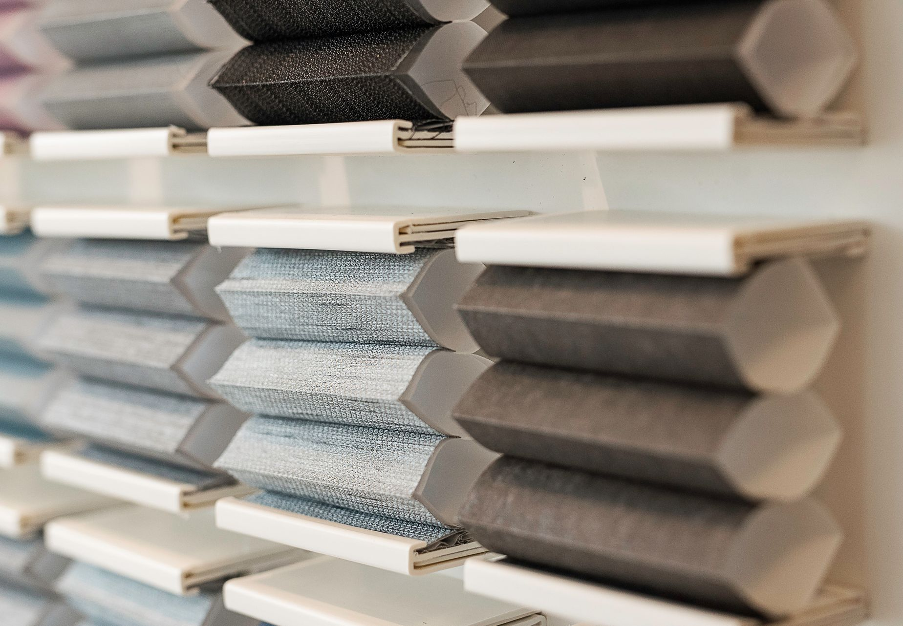 Row of gray and white textured fabric swatches on display shelves