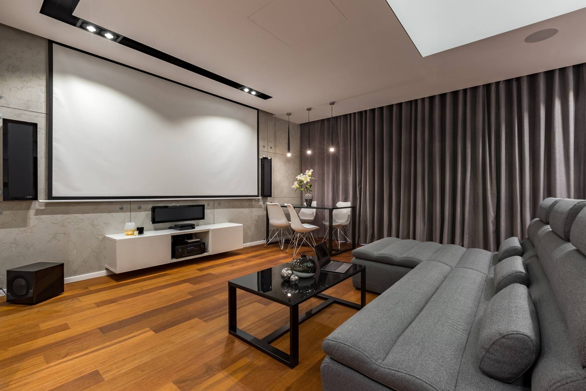 Home media room with a large projector screen and modern curtains drawn shut for the movie