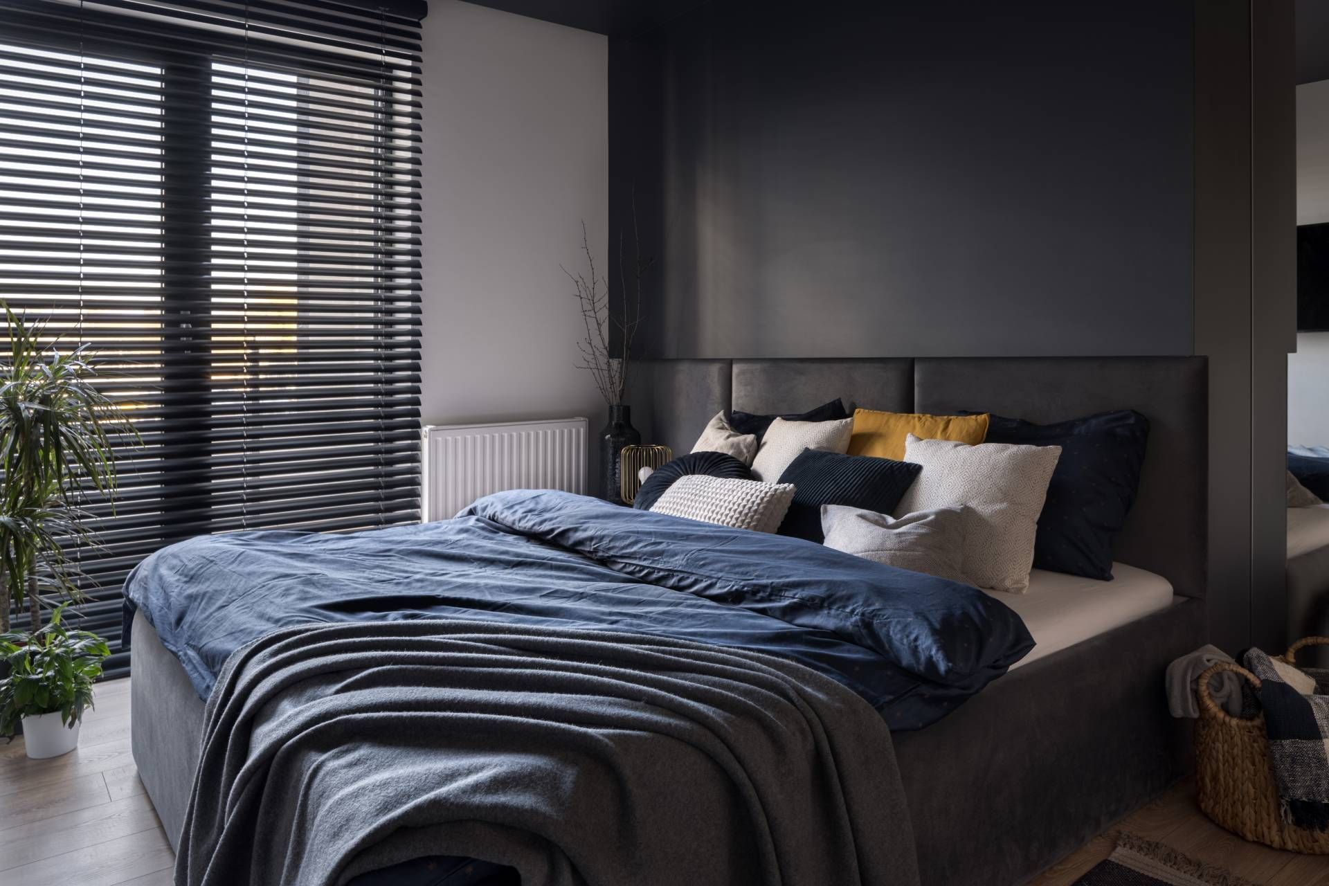Modern bedroom with a cozy, moody atmosphere and window blinds partially opened to let in light