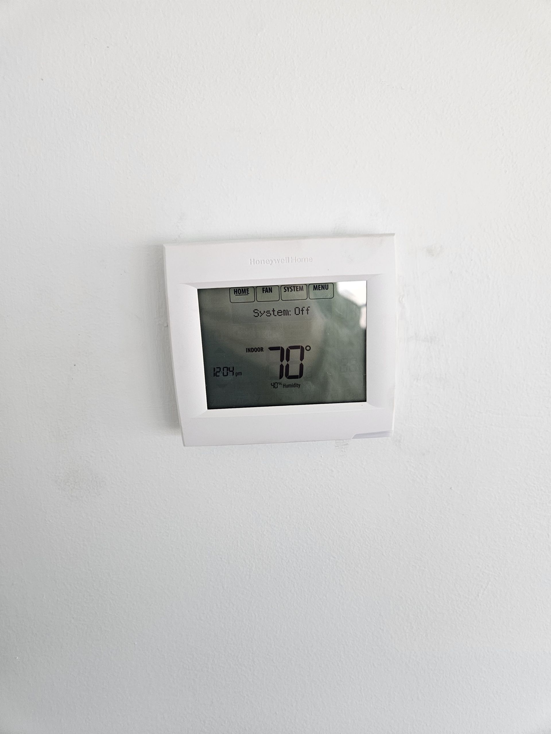 White wall with a small square opening and a partially visible digital display inside.