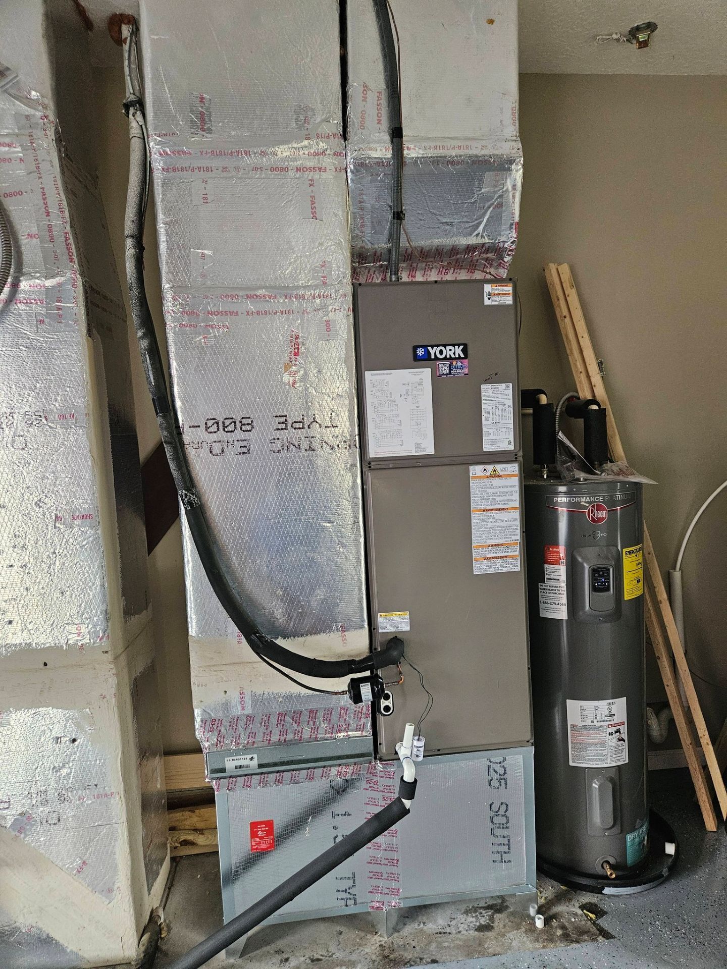 Basement HVAC equipment and ductwork with insulated pipes and a water heater