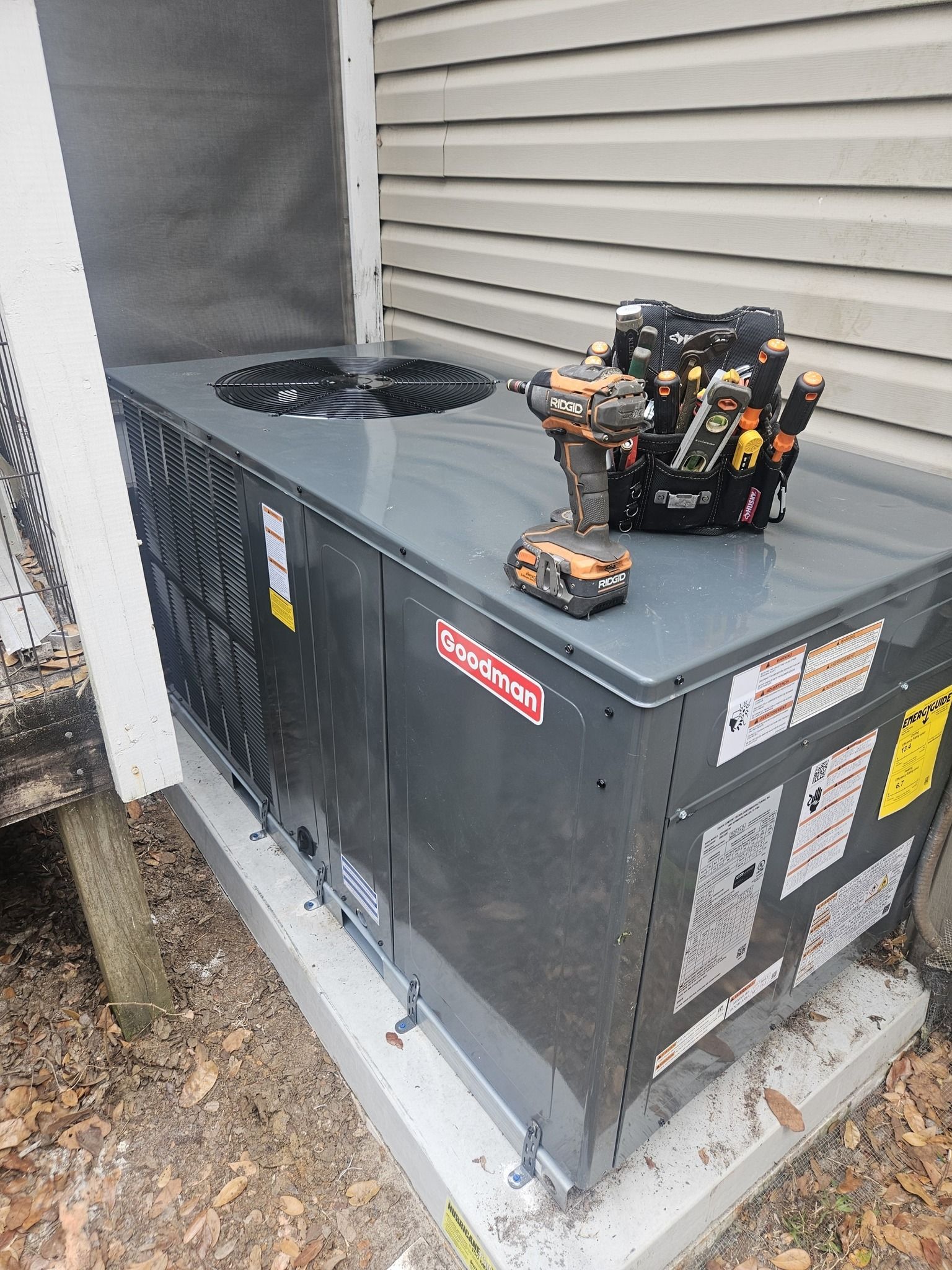 Outdoor HVAC unit beside a house with a small robot toy sitting on top