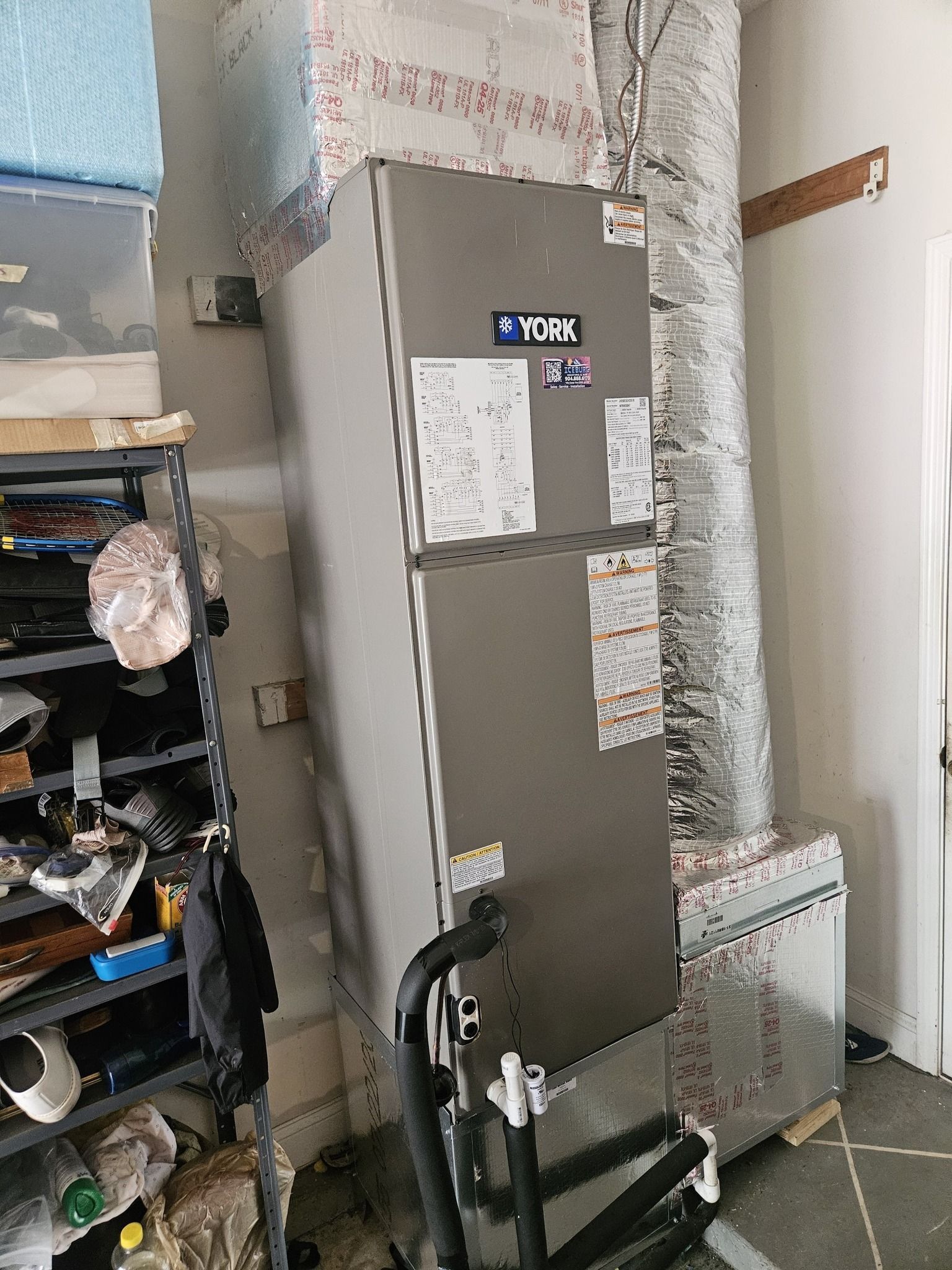 Gray utility cabinet with papers attached, beside a small cart and shelving in a cluttered room