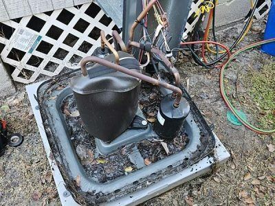 Outdoor HVAC compressor with copper tubing and hoses in a concrete utility pad area