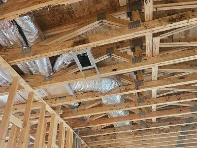 Wooden attic framing with exposed rafters and HVAC ducts during construction