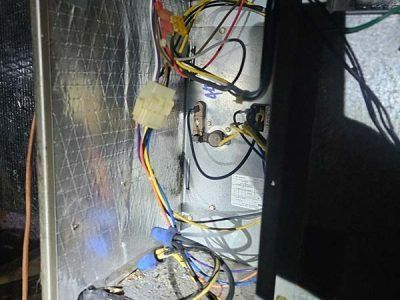 Electrical wiring and connectors inside a metal cabinet, with bundled red, yellow, blue, and black cables.