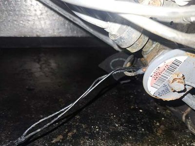 Close-up of a small electric motor with exposed wires and a dusty black surface.