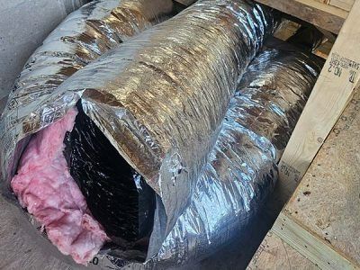 Insulated duct wrapped in silver foil, with pink fiberglass insulation exposed at one end.