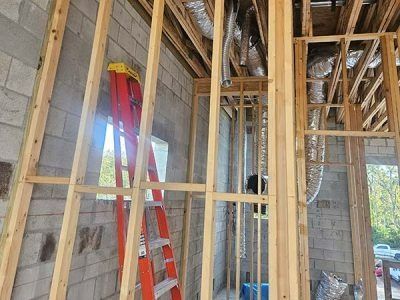 Interior construction site with wooden framing, concrete walls, and a red ladder near a window opening
