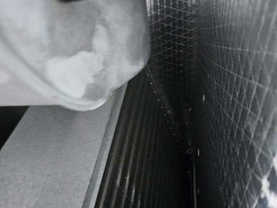 Close-up of a gray, textured surface beside a black ribbed panel and tiled wall corner.