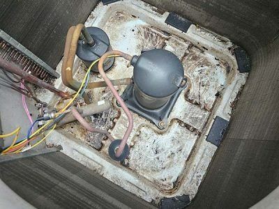 Open electrical box with wiring and two gray components inside a dirty, worn enclosure