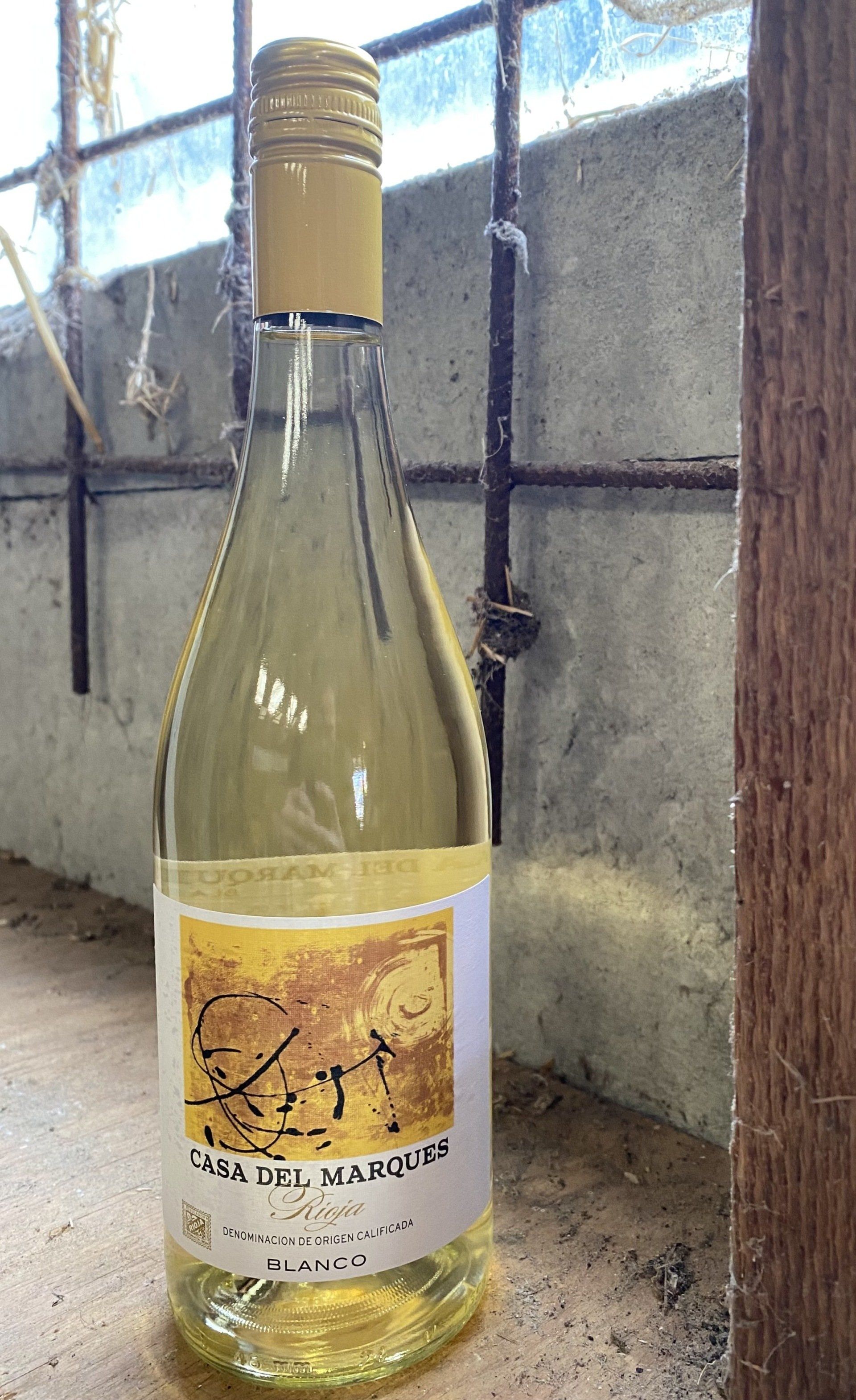 Fles witte wijn, etiket zichtbaar, op een reflecterend oppervlak.
