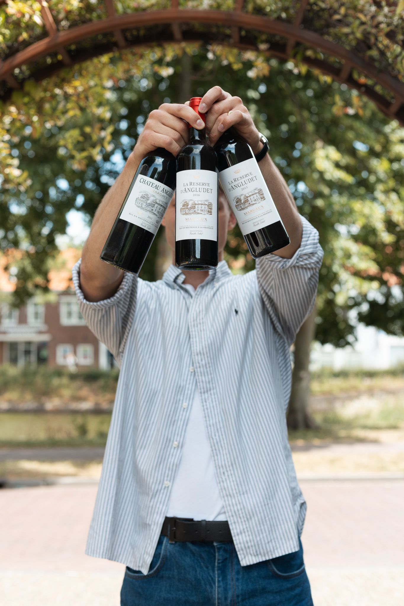 Iemand schenkt mousserende wijn uit een donkere fles in een glas.