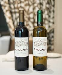 Twee flessen Chateau Argadens-wijn: een rode en een witte, op een witte tafel.