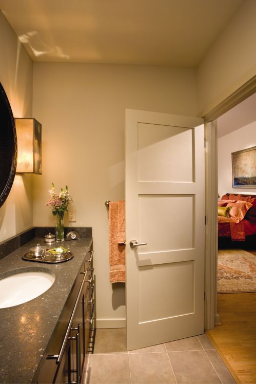 Bathroom with a vanity, sink, open door to a bedroom, and wall sconce. Bathroom with a vanity, sink, open door to a bedroom, and wall sconce.