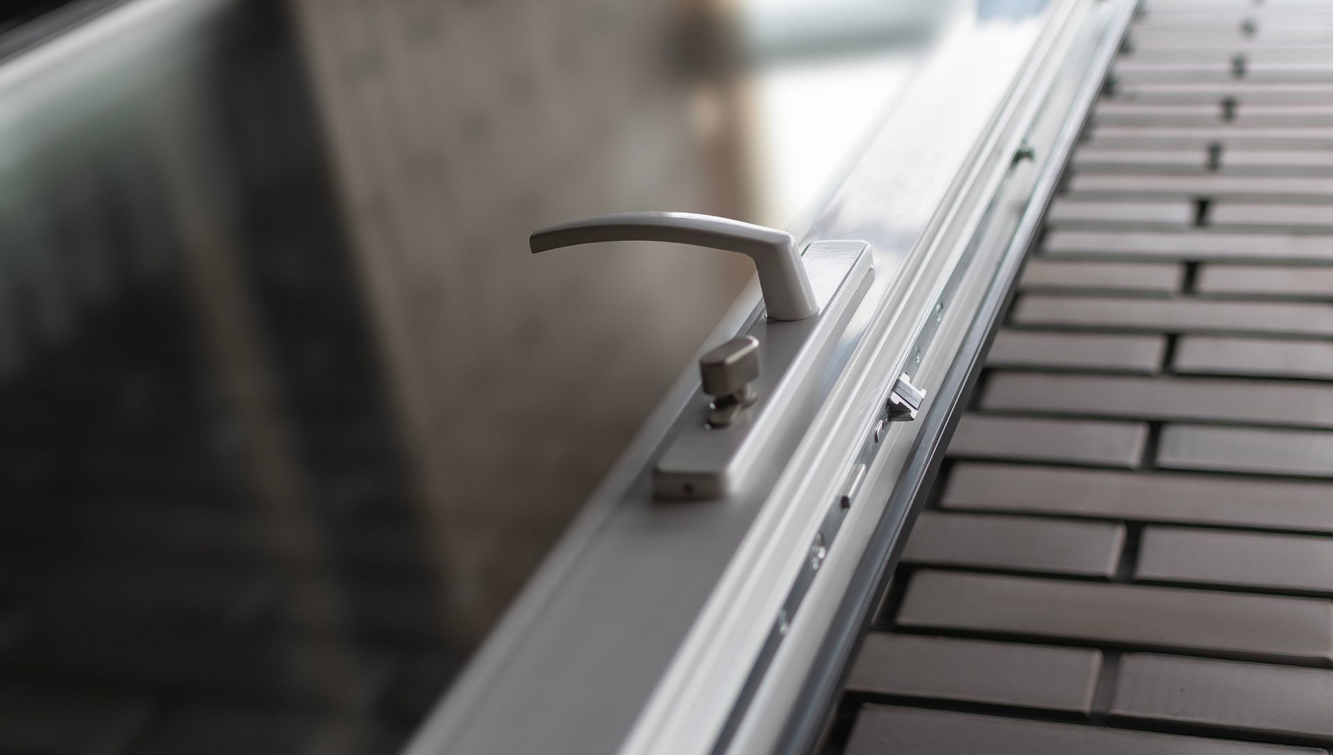 Close-up of a modern window handle and lock on a residential window frame.