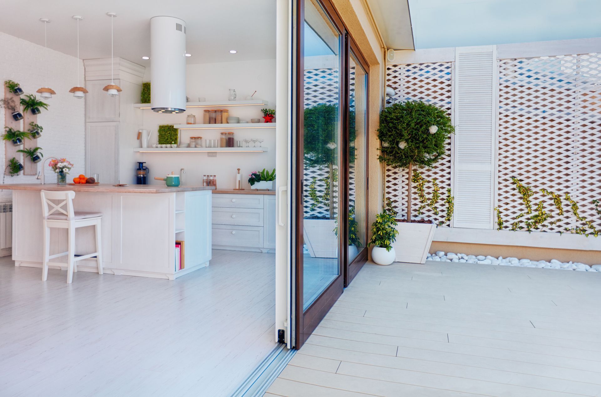 Bright white kitchen with open doors to a patio. Includes island, plants, and sliding glass doors. Bright white kitchen with open doors to a patio. Includes island, plants, and sliding glass doors.