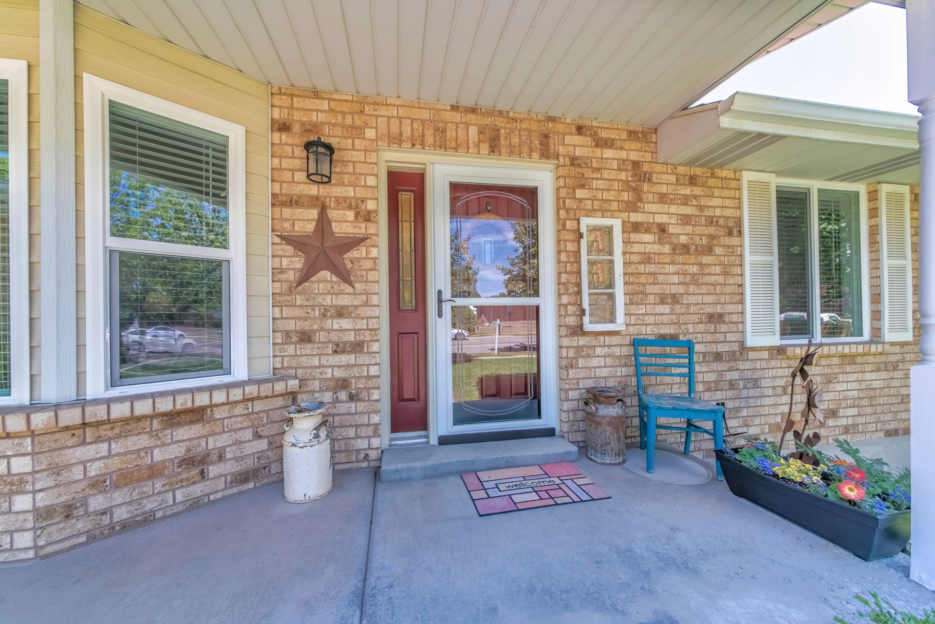 Home entrance with glass storm door over the burgundy door with side panel.