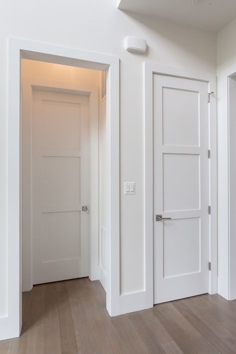 White interior doors with paneling in a hallway with wood flooring.
