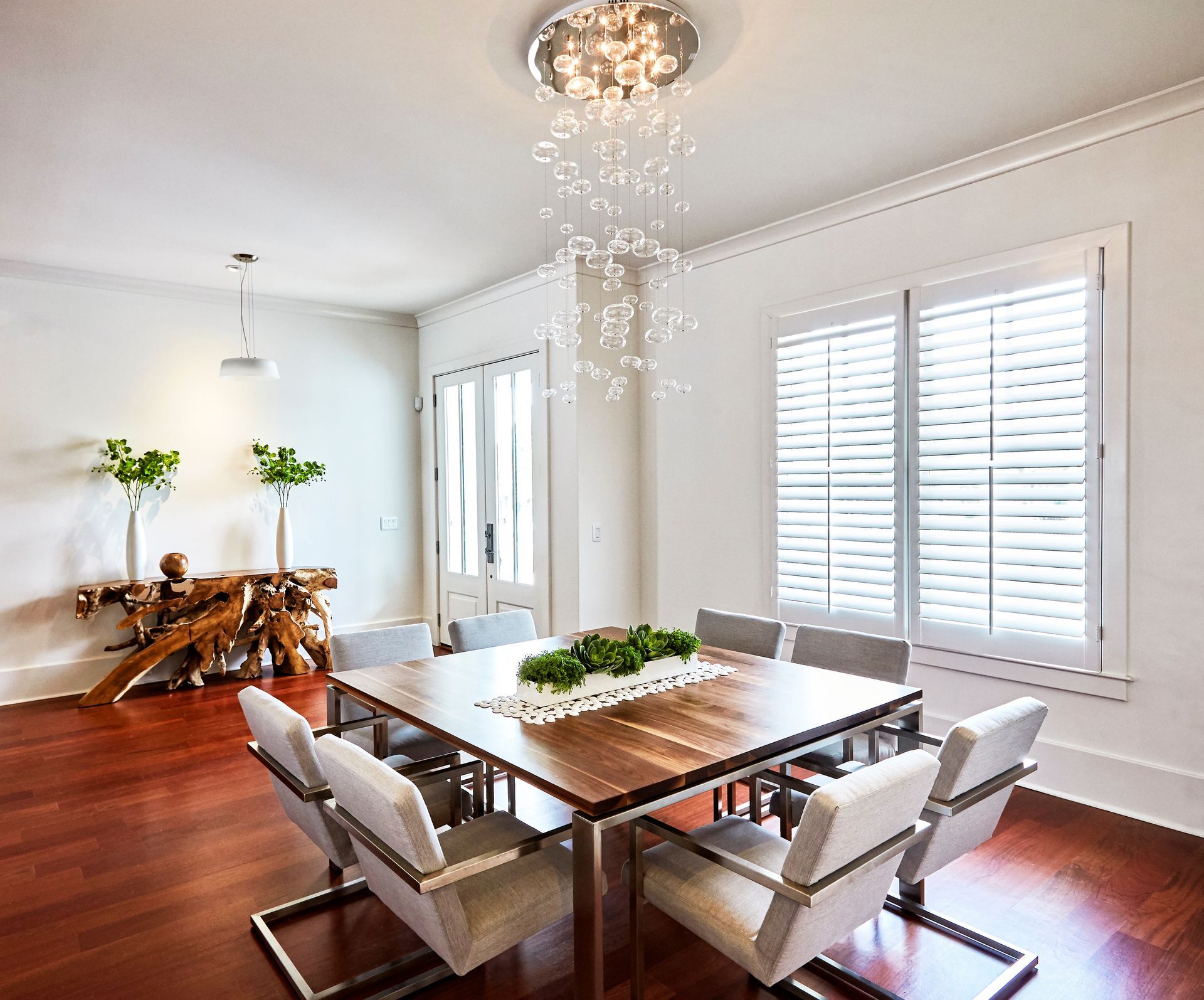 Dining room with wood table, modern chairs, chandelier, and hardwood floors.