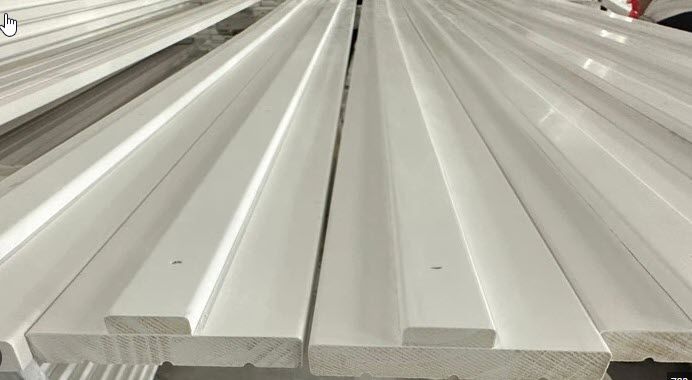 White wooden boards with a groove, stacked in rows.
