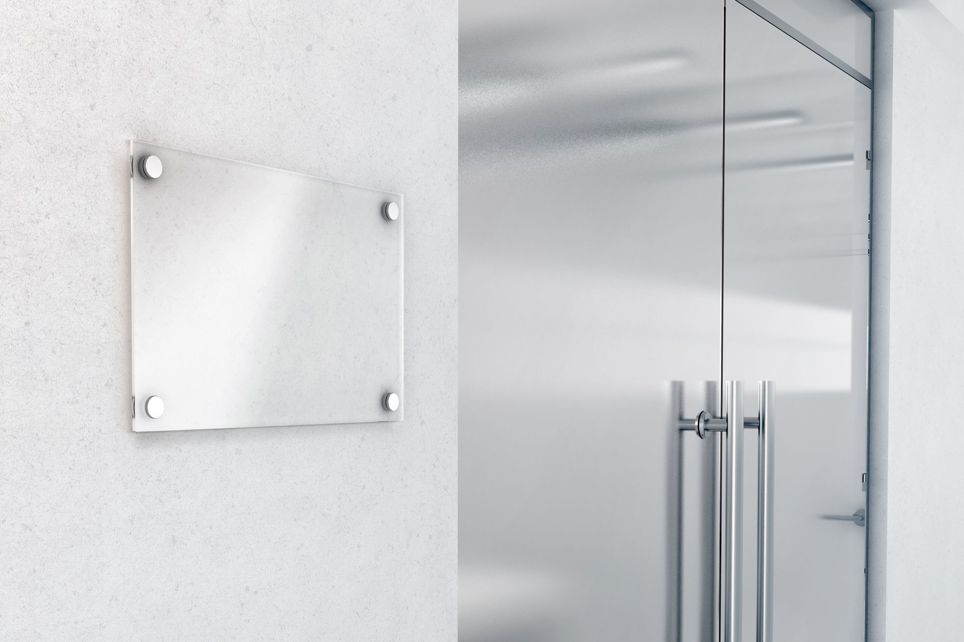 A blank, silver plaque mounted on a white wall, next to a glass door.