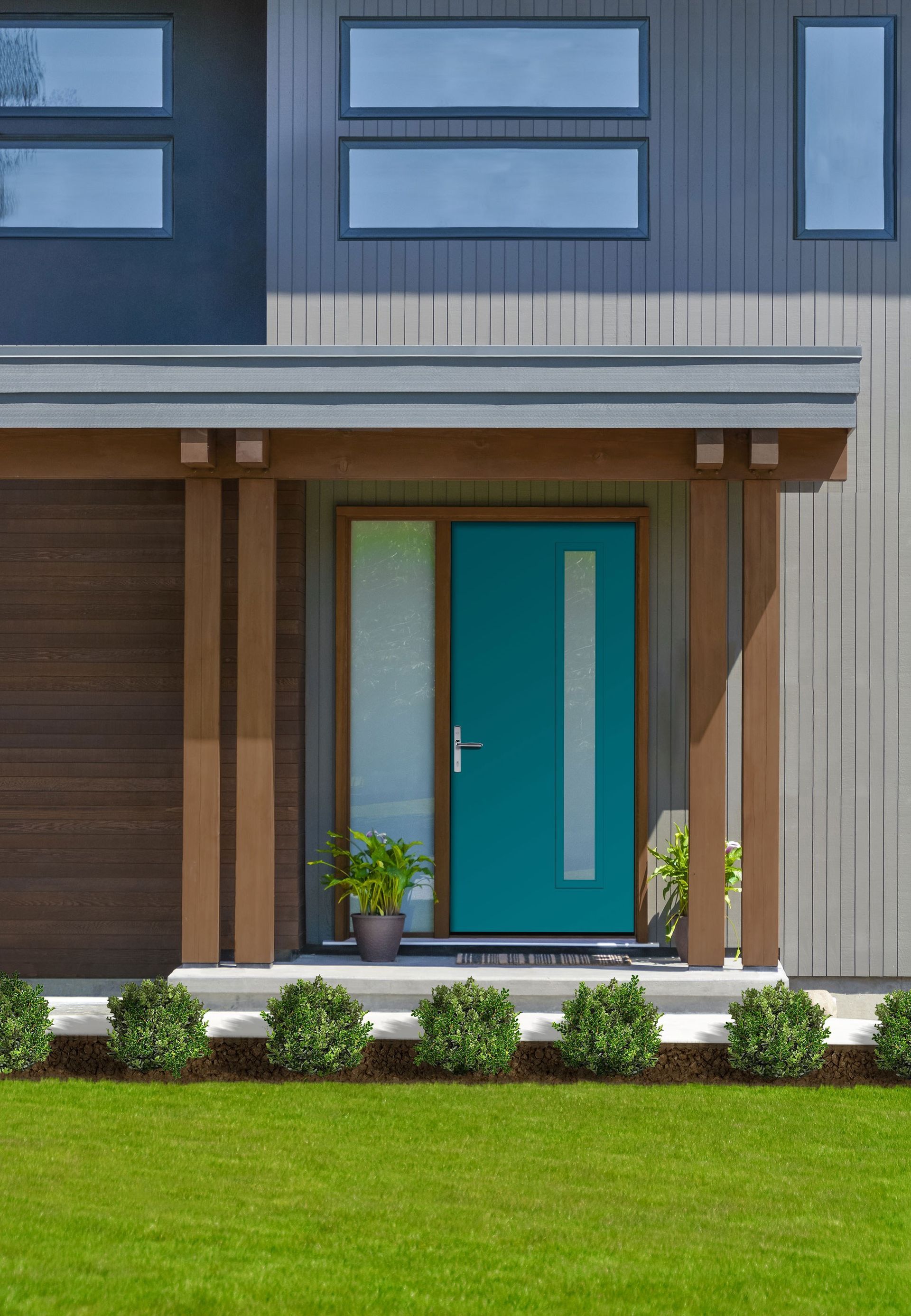 Teal front door with sidelight, beneath a brown awning, set in a modern gray house, with green lawn. Teal front door with sidelight, beneath a brown awning, set in a modern gray house, with green lawn.