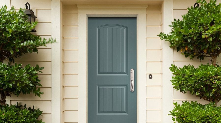 Blue front door centered on a beige house with shrubbery on each side. Blue front door centered on a beige house with shrubbery on each side.