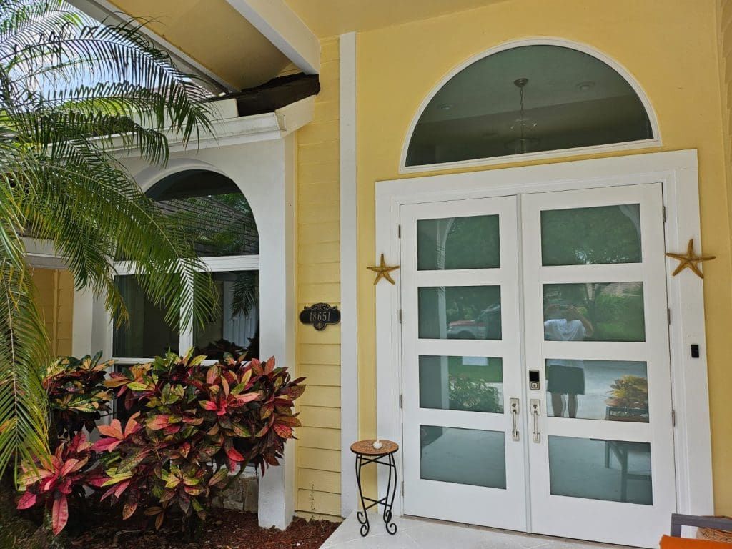 Yellow house entrance with arched window and double doors. White trim, star accents. Yellow house entrance with arched window and double doors. White trim, star accents.