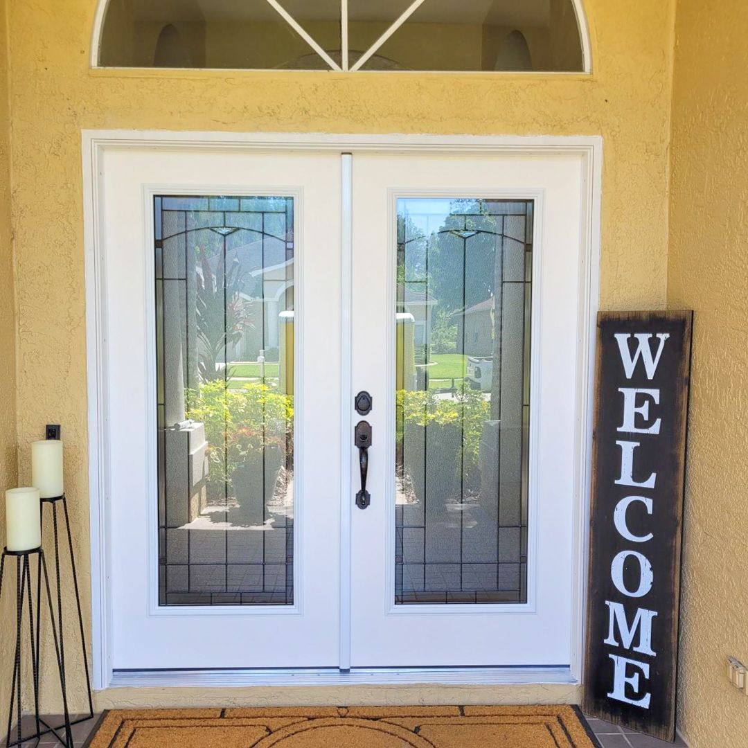 White double doors with glass panels and a welcome sign in front. White double doors with glass panels and a welcome sign in front.