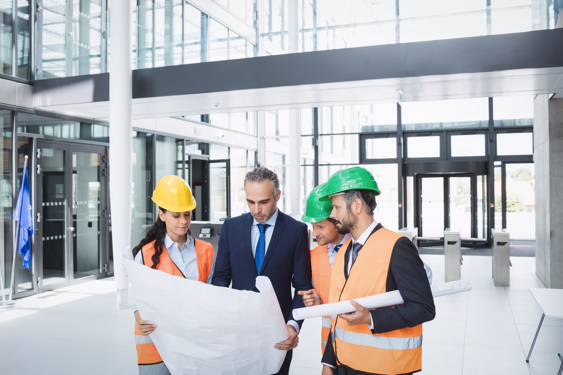 Engineers in hard hats reviewing blueprints in a bright modern lobby
