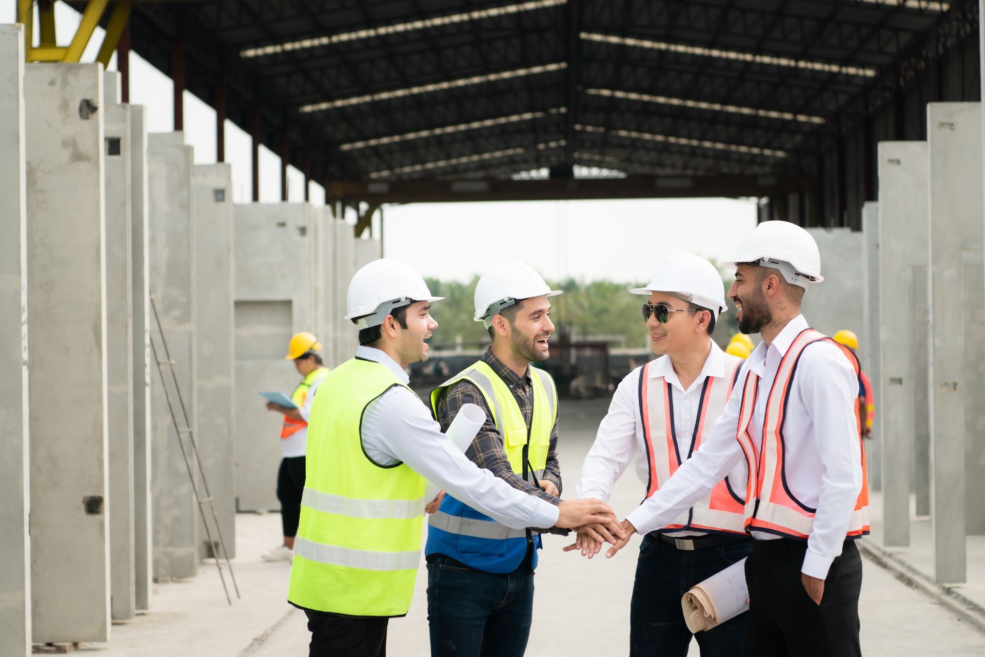 Engineers in hard hats and safety vests shaking hands in a concrete construction site