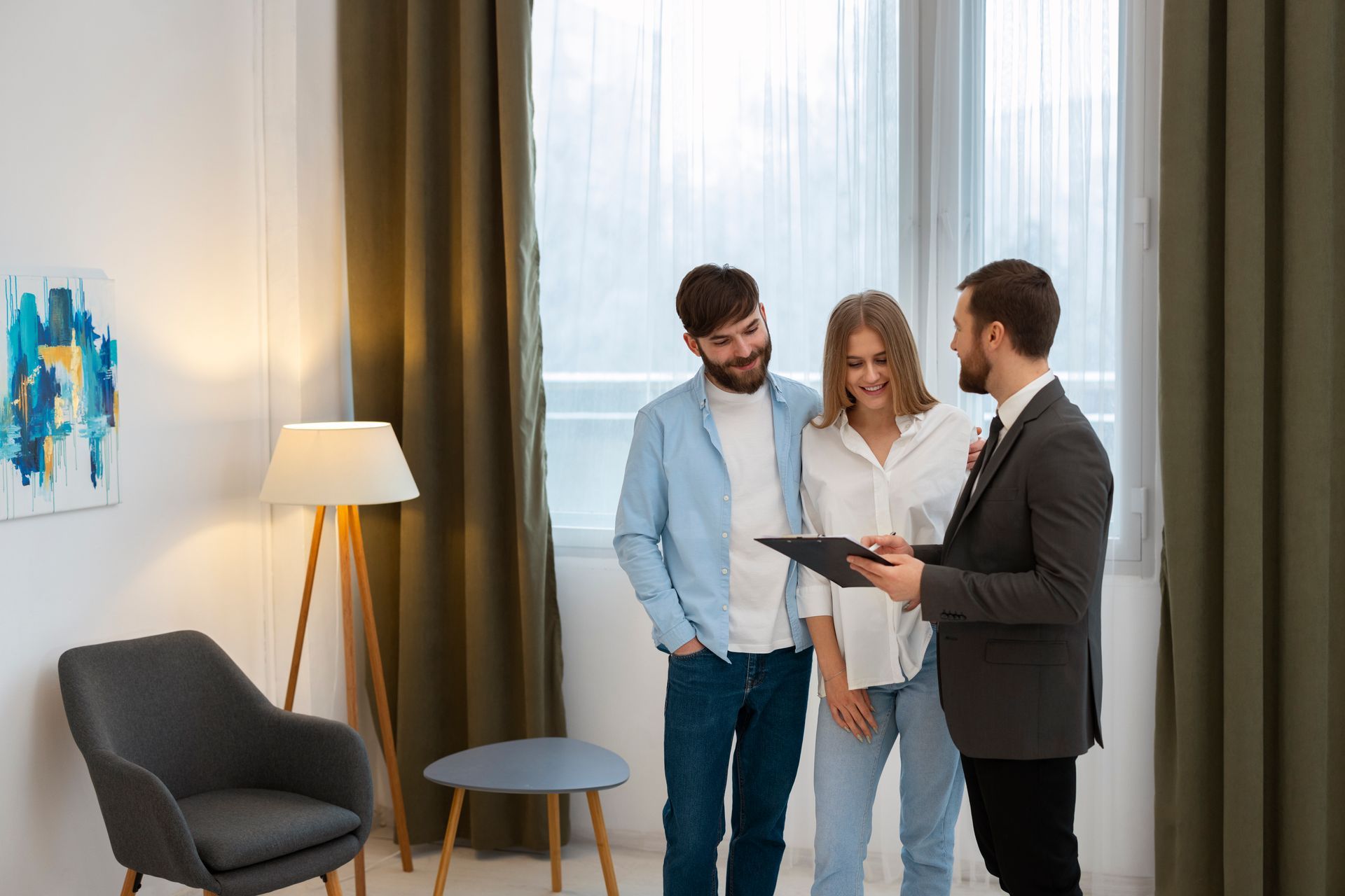 Three people discussing a document in a bright living room near a window and floor lamp