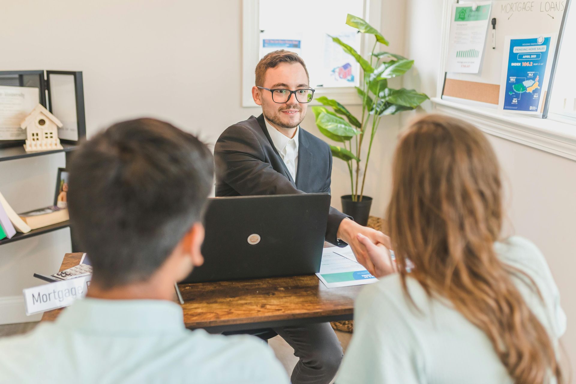 Three people in a meeting with a laptop in a bright office