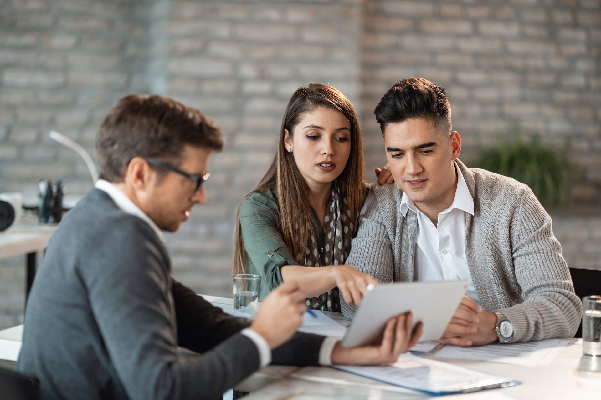 Three people reviewing documents at a conference table in an office setting