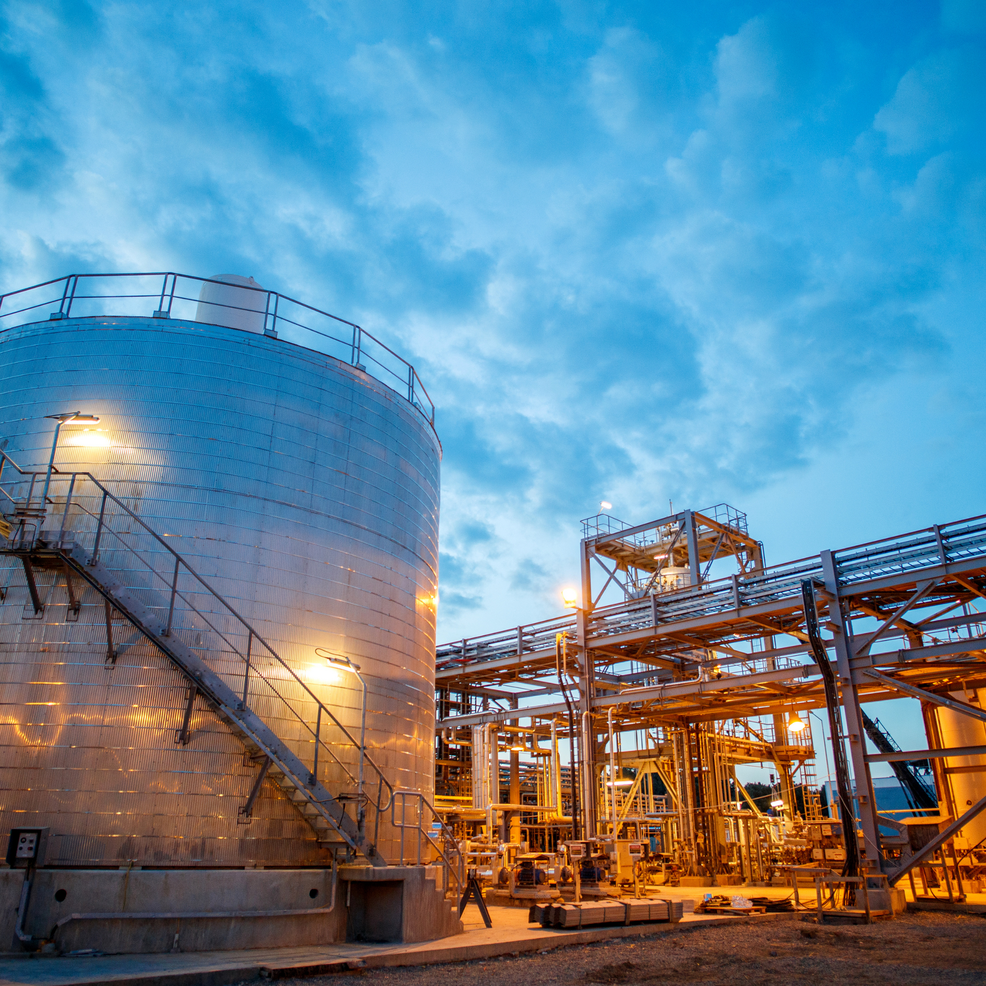 Large industrial tank with stairs, complex pipes and structures at dusk.