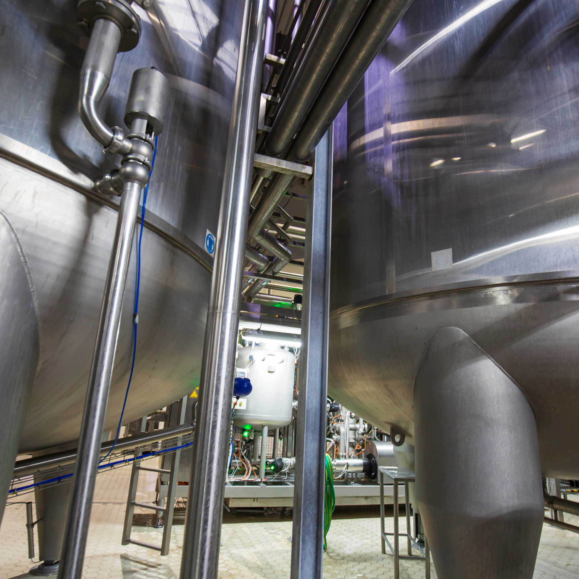 Stainless steel tanks and pipes in a factory setting.
