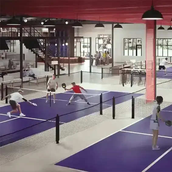 Indoor pickleball facility with players on purple courts, red ceiling, and a mezzanine.