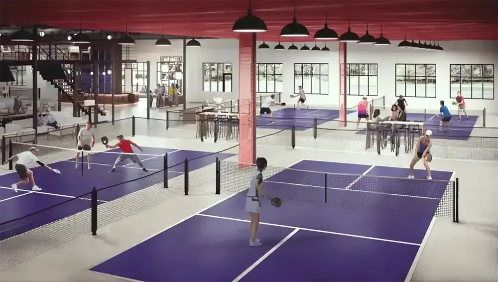 Indoor pickleball courts with players, cafe area, and red ceiling.