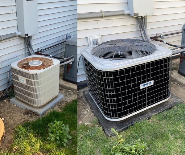 Old and new outdoor air conditioning units beside a house on a grassy yard.