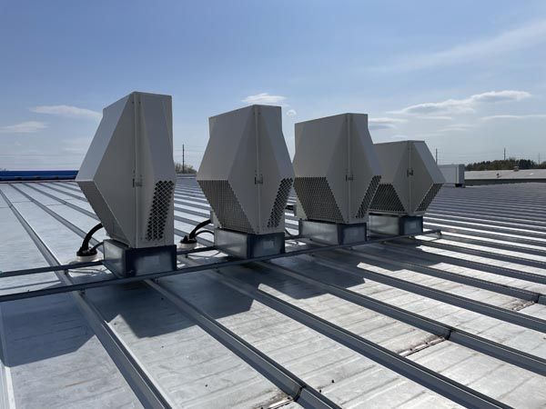 Rooftop ventilation units on a metal industrial roof under a blue sky