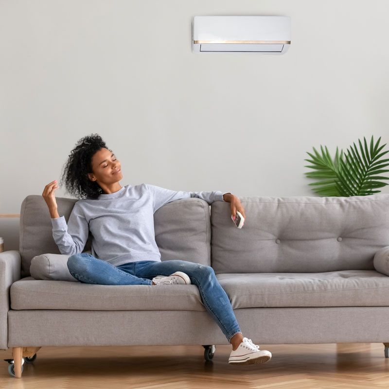 Woman relaxing on a gray sofa in a bright living room under a wall light