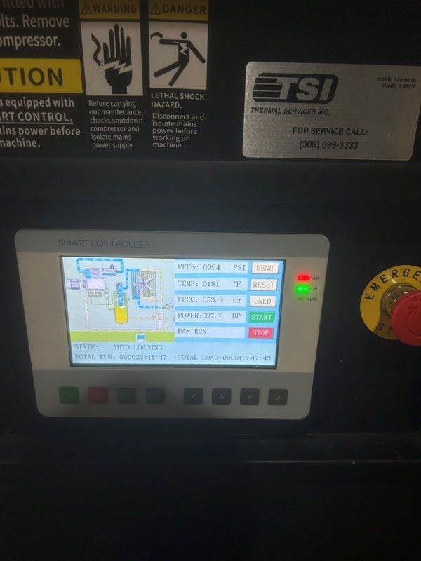 Industrial control panel with small touchscreen display and illuminated red and green indicator lights.