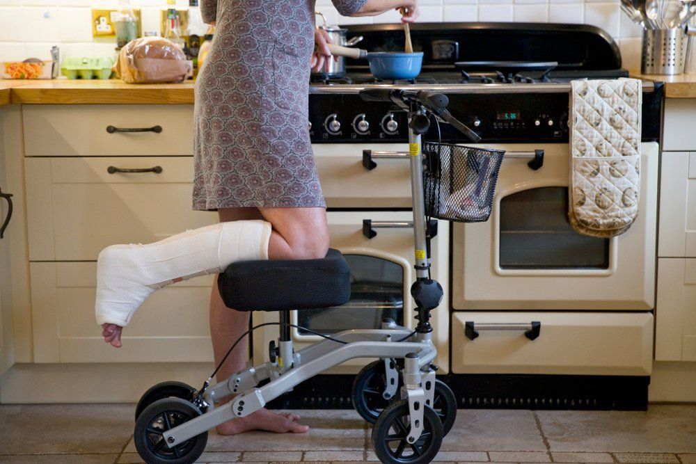 A Woman with A Cast on Her Leg Is Using a Knee Walker in The Kitchen — Toukley World of Bikes In Toukley, NSW