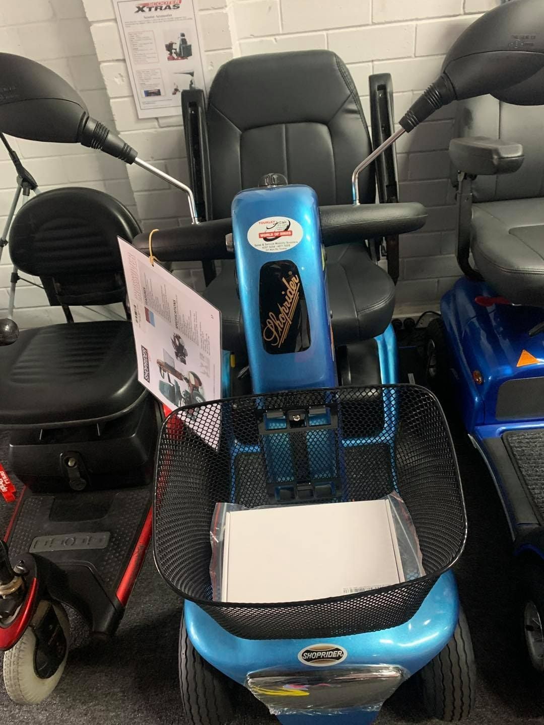 A Blue Mobility Scooter with A Basket Is Sitting in A Showroom — Toukley World of Bikes In Toukley, NSW
