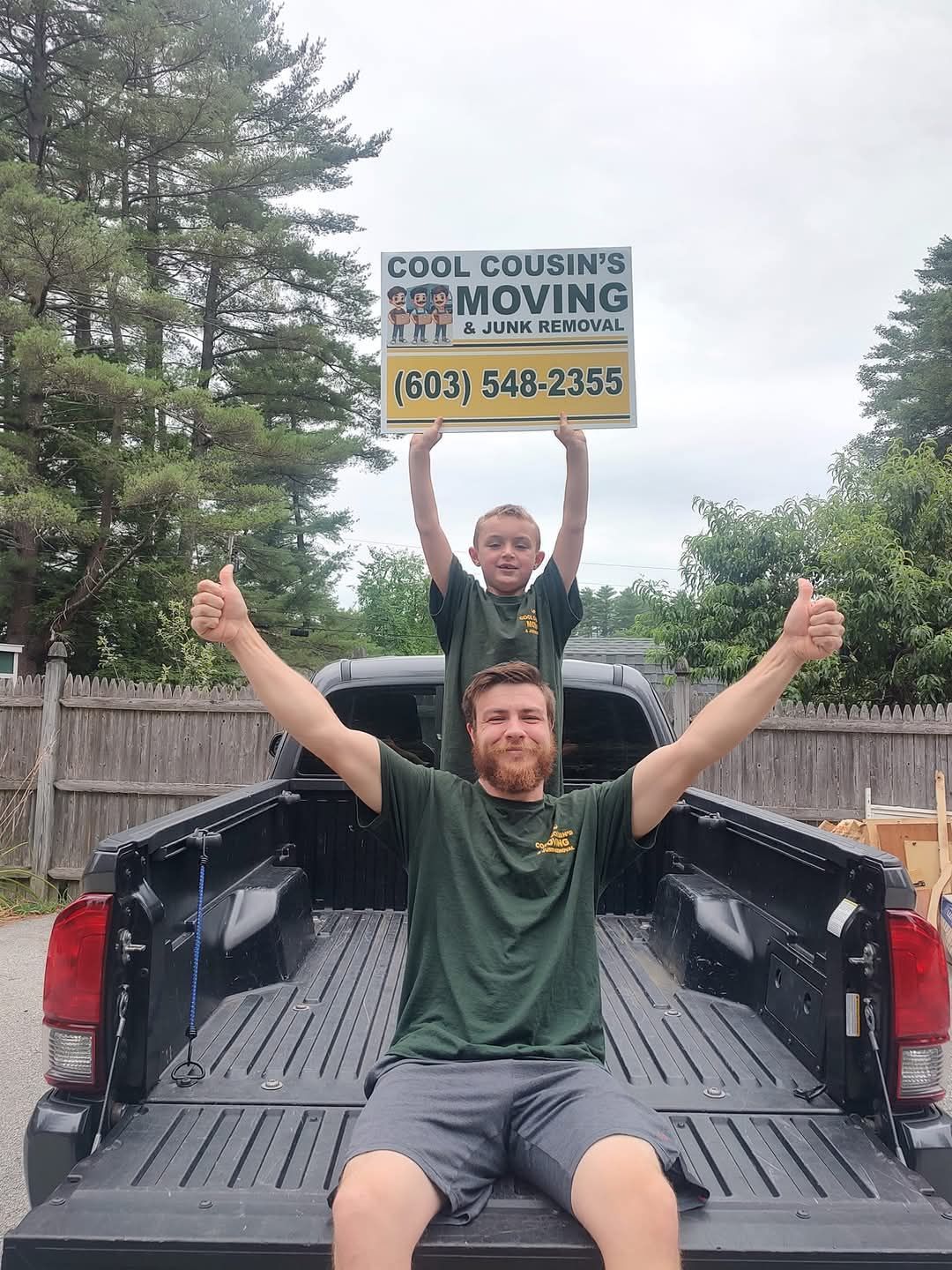 Two movers in a pickup truck, one holding a Cool Cousins Moving sign with phone number.